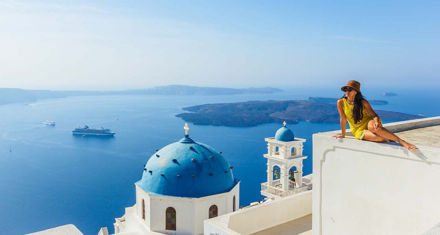 Sail towards the white washed buildings and bright blue domes of Santorini of a cruises of Greek Isles